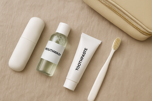 Dentora travel oral care essentials – toothbrush case, mini mouthwash, toothpaste, and manual toothbrush in a flat lay on neutral fabric background